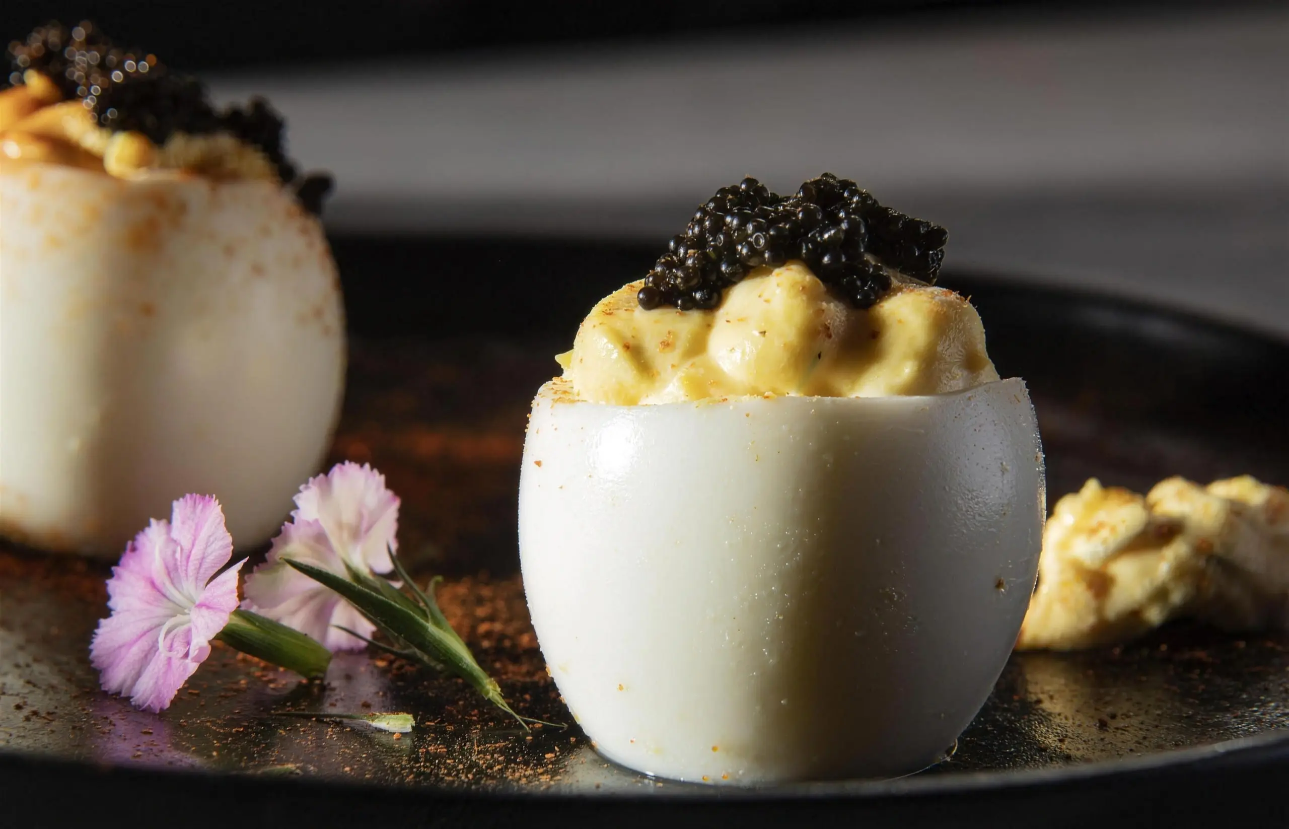 Œufs mimosa garnis de caviar, sur une assiette sombre
